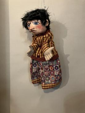 Tibougon ronchon, jeune garçon aux cheveux noirs, vêtu d'un pantalon bariolé et d'une veste à rayures jaunes et brunes