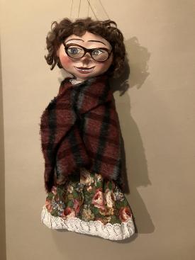 Femme brune à lunettes, vêtue d'une robe à fleurs et d'un châle