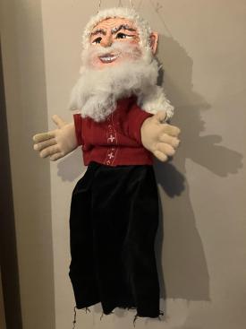 Vieil homme à la barbe et aux cheveux blancs, vêtu d'un pantalon noir et d'une veste rouge