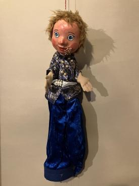 Garçon vêtu d'un pantalon bleu et d'une veste, des perles sortent de sa bouche