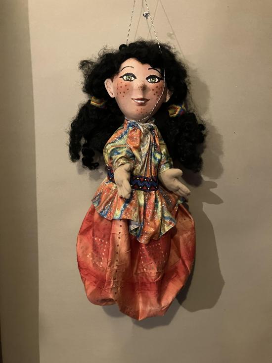 Jeune ville noiraude aux yeux verts, avec des taches de rousseur, vêtue d'un pantalon large orange et d'une casaque multicolore