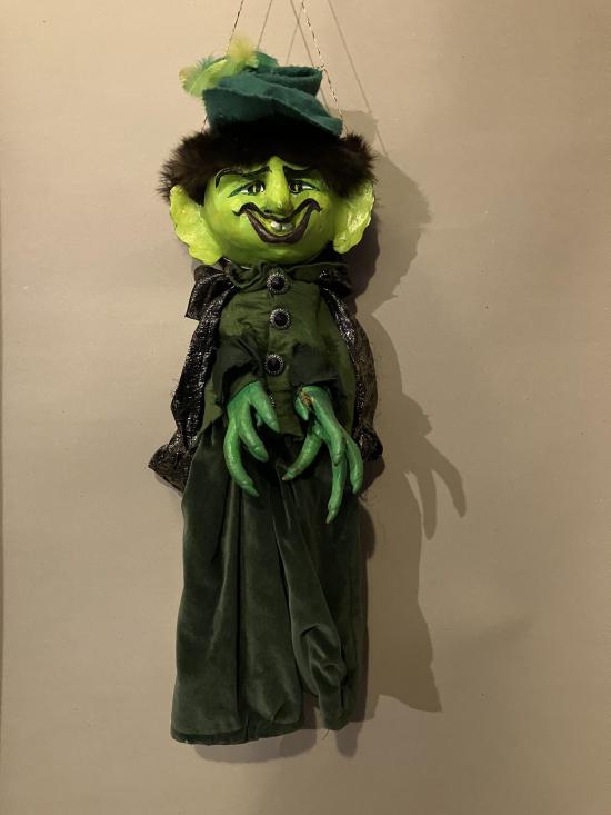Diable à la tête et aux mains vertes, vêtu d'un costume vert et d'une cape grise