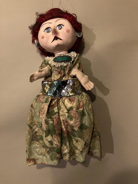 Femme coiffée d'un chignon rouge et vêtue d'une robe à fleurs maintenue par une grosse ceinture