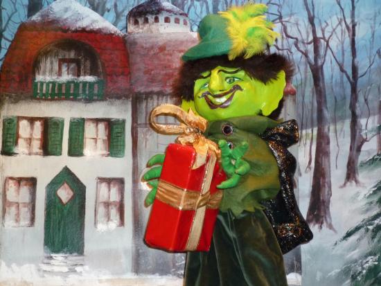 Garougriffou devant la maison de la femme au chignon rouge avec un cadeau dans les mains